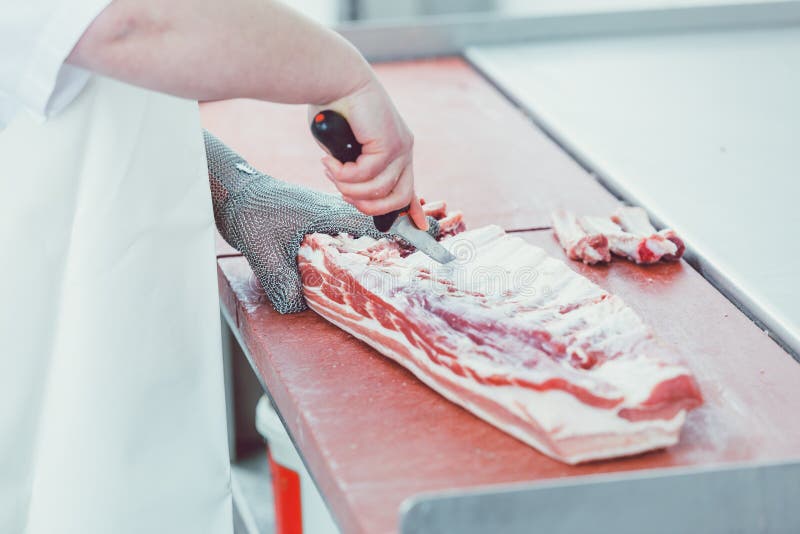 Butcher cutting meat for further processing with knife