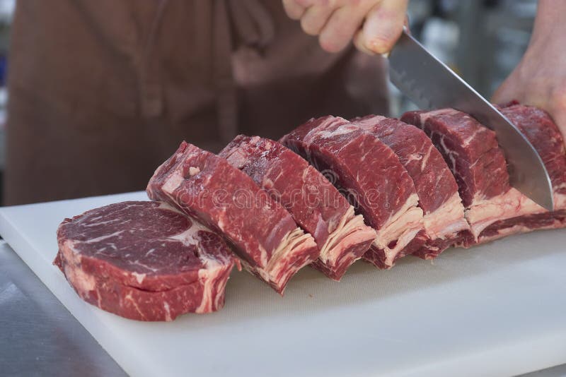Butcher Cutting Beef in the Kitchen. Closeup of Hands with a Knife and