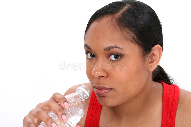 A studio portrait of a young African American woman, drinking bottled water. A studio portrait of a young African American woman, drinking bottled water.