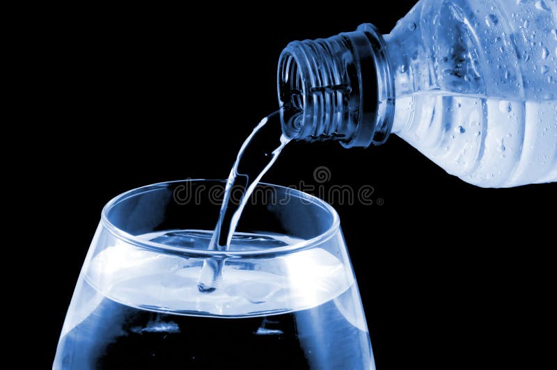 Bottled water being poured into a glass against blackbackground. Bottled water being poured into a glass against blackbackground