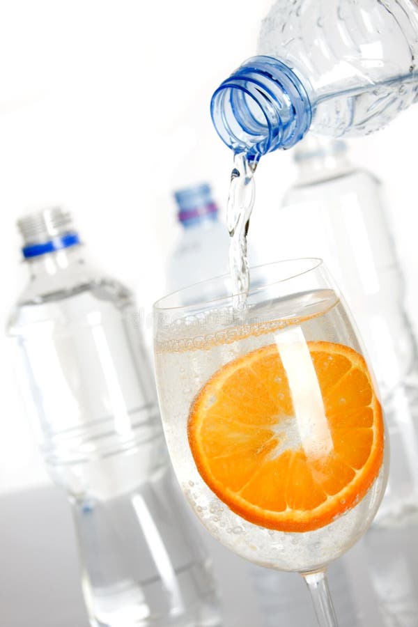 Bottled water poured in a glass with slice of orange. Bottled water poured in a glass with slice of orange