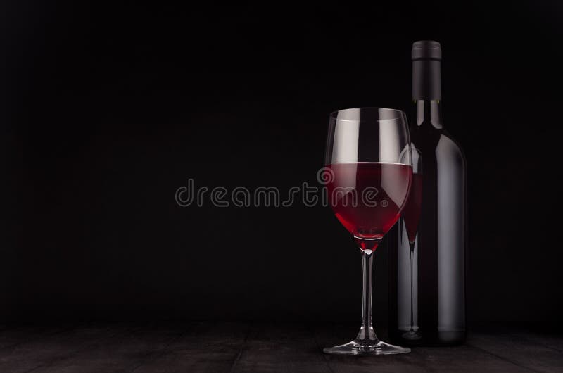 Bottle of red wine and wine glass mock up on elegant dark black wooden background, copy space. Bottle of red wine and wine glass mock up on elegant dark black wooden background, copy space