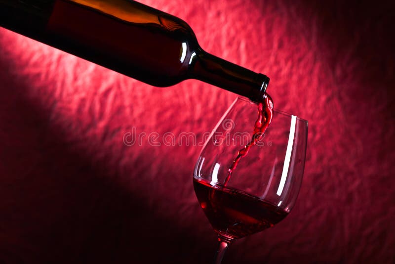 Bottle and glass of red wine on a dark red background. Bottle and glass of red wine on a dark red background
