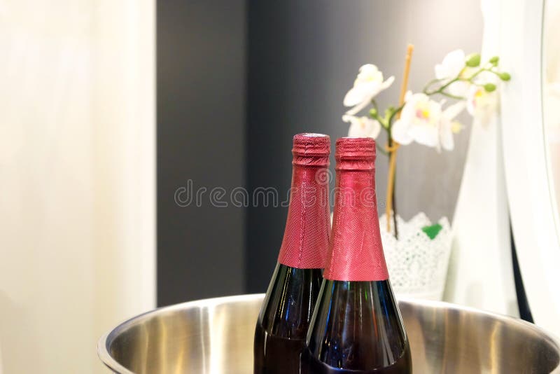 Butelki czerwone wino na lodzie w szklanym zbiorniku Obok kwiatów na lustrzanym tle zdjęcia royalty free Butelki czerwone wino na lodzie w szklanym zbiorniku Obok kwiatów na lustrzanym tle zdjęcia royalty free