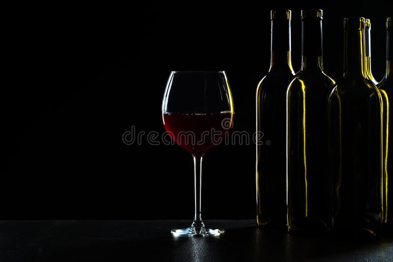 Bottles of wine and different glasses of wine on a dark background. Bar Concept with a Wine Bottle, a Wine Glass and a Cocktail on a Black Background