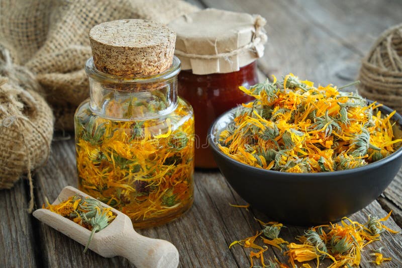 Butelki z wlewami kalendula zdrowe kwiaty marigold w miseczce i soli calendula na drewnianym stole. medycyna ziołowa