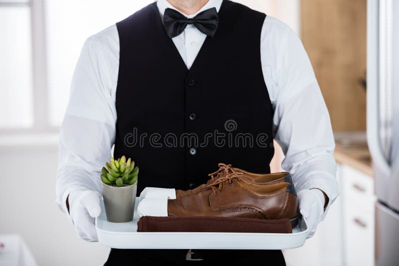 Butler Carrying Pair Of Brown Shoes
