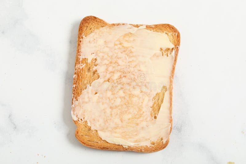 Slice of White Buttered Toast with a Bite Taken Out of One Corner