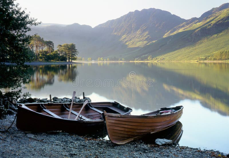 First light on Buttermere, in the Lake district, Cumbria. The foreground rowboats are used for fishing, or for pleasure. Haystacks is reflected in the distance, it was the favourite mountain of famous Cumbrian author, Alfred Wainwright, and where his ashes were scattered upon his death. First light on Buttermere, in the Lake district, Cumbria. The foreground rowboats are used for fishing, or for pleasure. Haystacks is reflected in the distance, it was the favourite mountain of famous Cumbrian author, Alfred Wainwright, and where his ashes were scattered upon his death