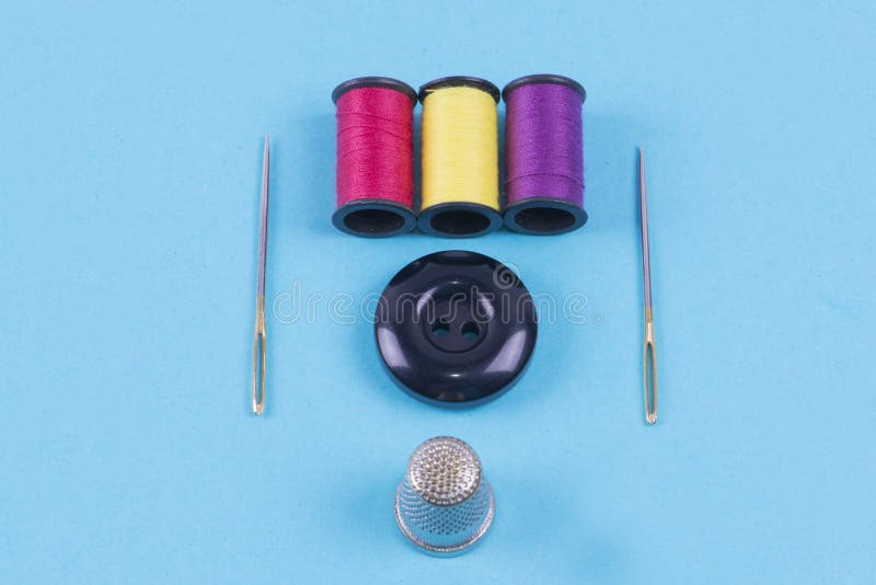 Sewing items - thimble, needle, measuring tape, spools of blue thread,  including pins. Blue fabric for sewing on background Stock Photo - Alamy