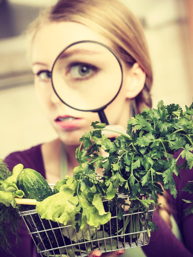 Woman looking through magnifier at vegetables basket