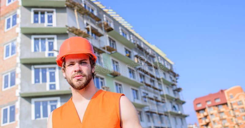 Byggmästaren i orange väst och hjälm arbetar konstruktionsplatsen Säkerhet av byggmästaren på arbetsbegreppet Grabb i skyddande h royaltyfri fotografi Byggmästaren i orange väst och hjälm arbetar konstruktionsplatsen Säkerhet av byggmästaren på arbetsbegreppet Grabb i skyddande h royaltyfri fotografi