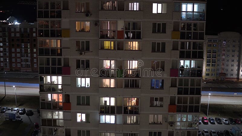 Bâtiment à plusieurs étages grand le soir Dans les fenêtres des appartements les gens sont occupés avec leurs propres affaires banque de vidéos