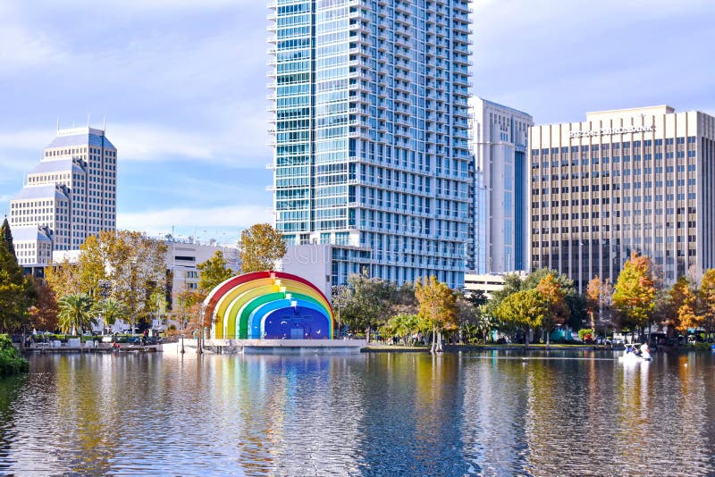 Orlando, Florida . December 24, 2018. Colorful buildings ,autumn forest at Lake Eola Park and swan boat on cloudy sky background in Orlando Downtown area 1. Orlando, Florida . December 24, 2018. Colorful buildings ,autumn forest at Lake Eola Park and swan boat on cloudy sky background in Orlando Downtown area 1
