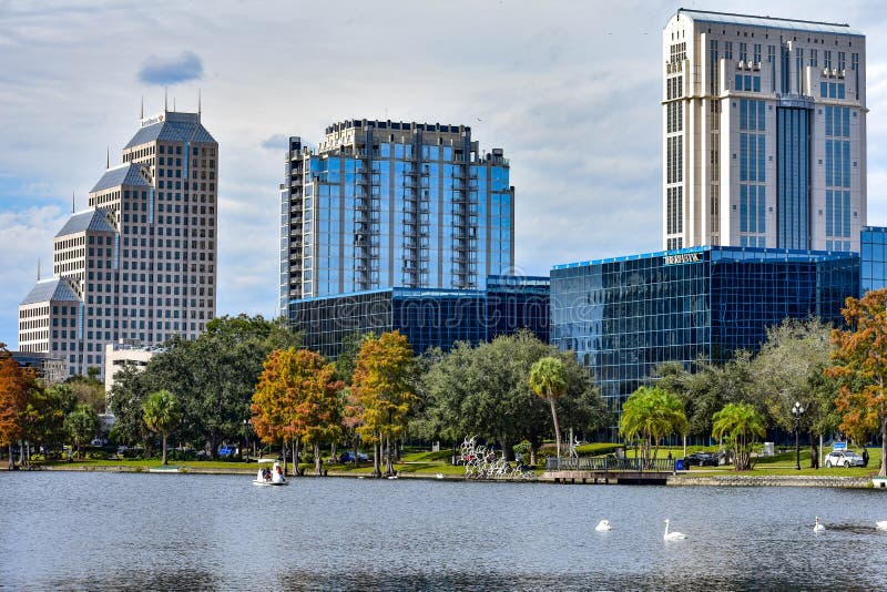 Orlando, Florida. December 24, 2018 Colorful buildings , autumn forest and swan boats in Eola Lake Park at Orlando Downtown 1. Orlando, Florida. December 24, 2018 Colorful buildings , autumn forest and swan boats in Eola Lake Park at Orlando Downtown 1