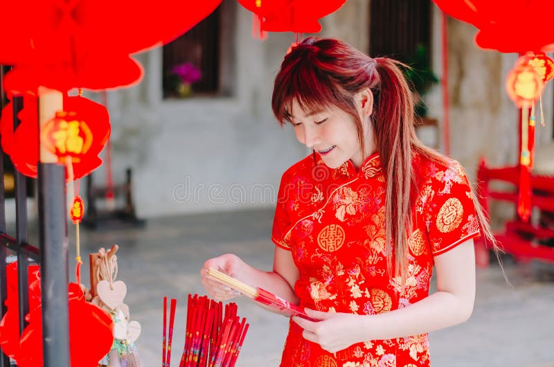 Bär den charmiga härliga asiatiska kvinnan för ståenden cheongsam för att klä upp för att välja att köpa rökelsen, i det kinesisk arkivfoton Bär den charmiga härliga asiatiska kvinnan för ståenden cheongsam för att klä upp för att välja att köpa rökelsen, i det kinesisk arkivfoton