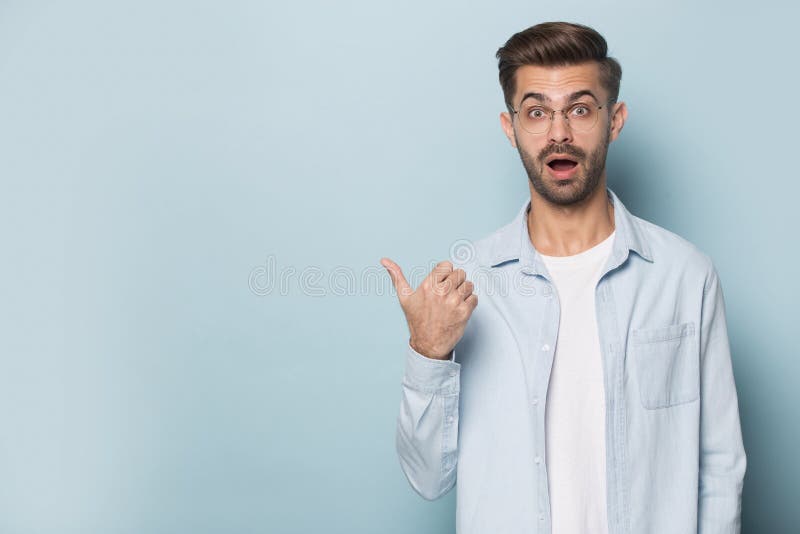Bärande exponeringsglas för förvånad rolig man som åt sidan pekar fingret på copyspace arkivfoton Bärande exponeringsglas för förvånad rolig man som åt sidan pekar fingret på copyspace arkivfoton