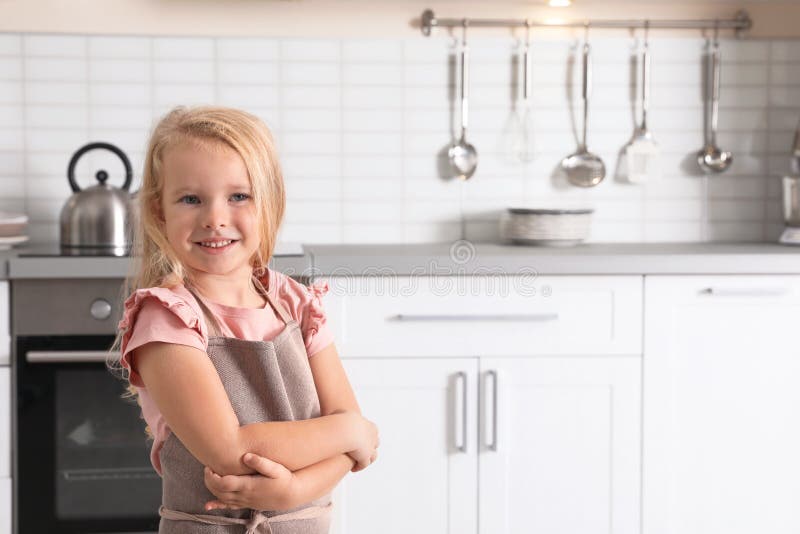Bärande förkläde för gullig liten flicka nära ugnen i kök arkivbild Bärande förkläde för gullig liten flicka nära ugnen i kök arkivbild