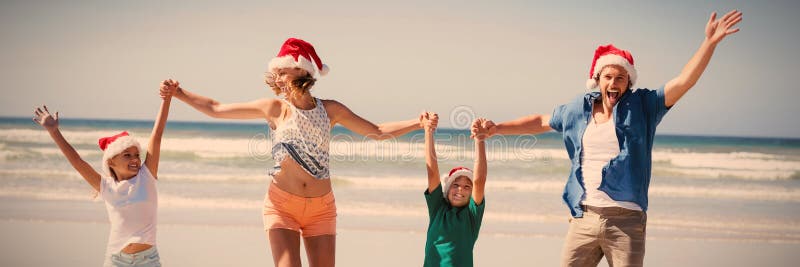 Bärande jultomtenhatt för gladlynt familj, medan hoppa på stranden royaltyfri bild Bärande jultomtenhatt för gladlynt familj, medan hoppa på stranden royaltyfri bild