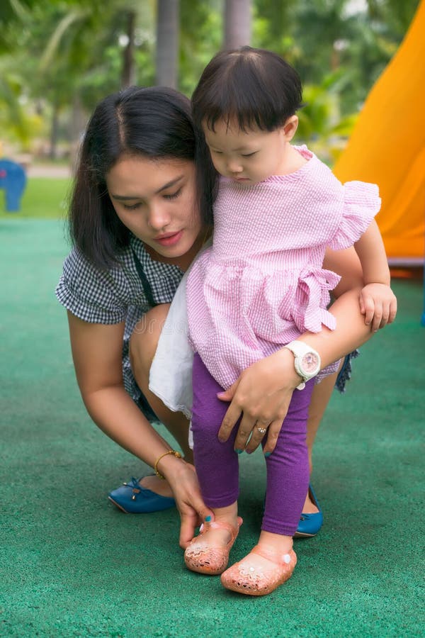 Bärande skor för asiatisk ung moderhjälpdotter royaltyfri fotografi Bärande skor för asiatisk ung moderhjälpdotter royaltyfri fotografi