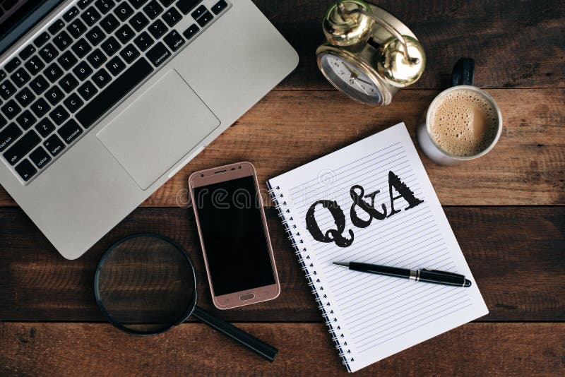 Bärbar dator, klocka, telefon, förstoringsglas, kaffe och anteckningsbok med Q&A-ord arkivbilder Bärbar dator, klocka, telefon, förstoringsglas, kaffe och anteckningsbok med Q&A-ord arkivbilder