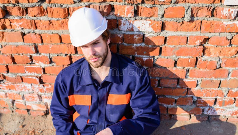 Bärtiger hübscher Erbauer des Kerlschutzhelms Nehmenminute zum sich zu entspannen Mannnehmenbruch-Arbeitstag an der Baustelle stockfotografie Bärtiger hübscher Erbauer des Kerlschutzhelms Nehmenminute zum sich zu entspannen Mannnehmenbruch-Arbeitstag an der Baustelle stockfotografie