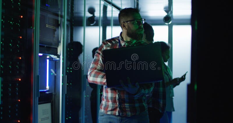 Bärtiger IT-Ingenieur unter Verwendung des Laptops im Serverraum lizenzfreie stockfotografie Bärtiger IT-Ingenieur unter Verwendung des Laptops im Serverraum lizenzfreie stockfotografie