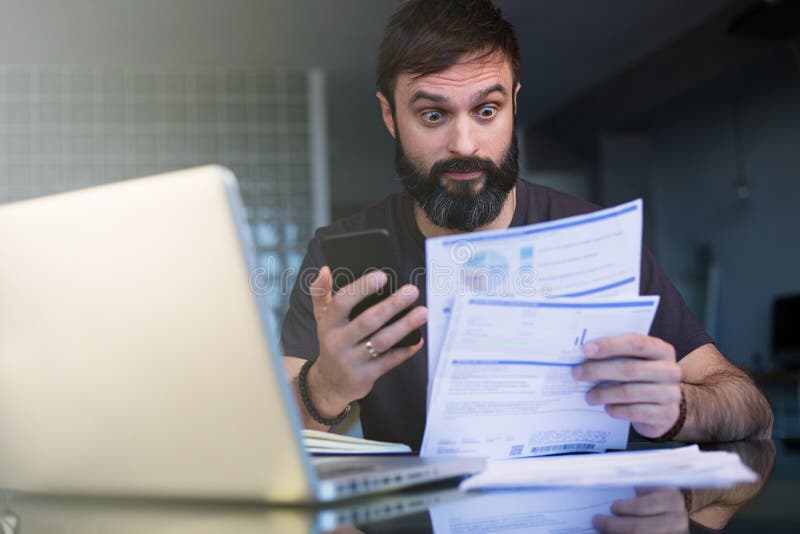 Bärtiger junger Mann, der zu Hause mit dem Laptop grast Dokumente arbeitet Geschäftsmann, der zu Hause Büro der Schreibarbeit dur lizenzfreies stockbild Bärtiger junger Mann, der zu Hause mit dem Laptop grast Dokumente arbeitet Geschäftsmann, der zu Hause Büro der Schreibarbeit dur lizenzfreies stockbild