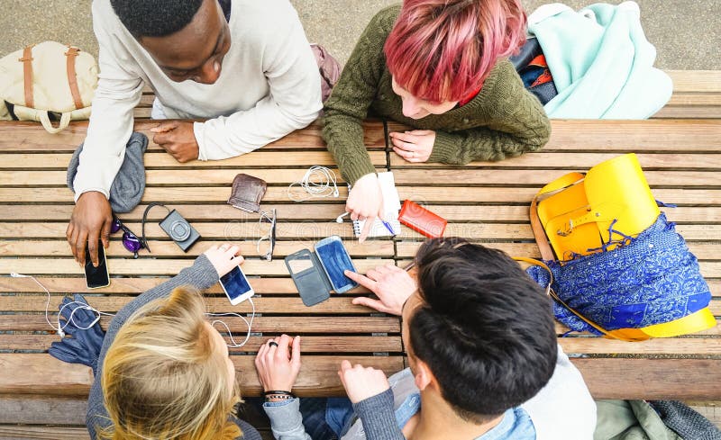 Top view of multiracial friends using mobile smart phone - Addiction concept with young people on new tech devices - Multicultural students having fun on social media. Top view of multiracial friends using mobile smart phone - Addiction concept with young people on new tech devices - Multicultural students having fun on social media