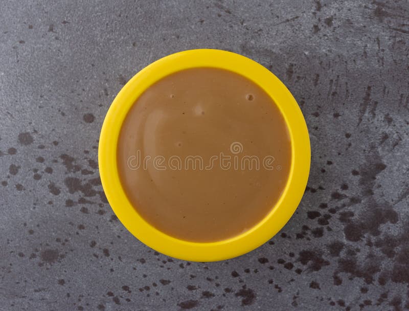 Bästa sikt av brun kalkonsky i en liten gul bunke på en grå bakgrund