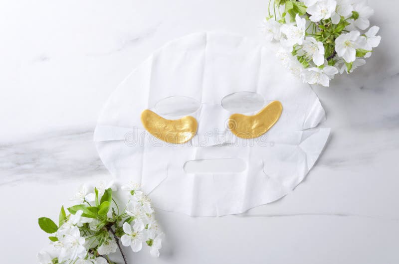 Bästa sikt av den ansikts- maskeringen och guld- lyxiga ögonlappar, blomningfilialer på vit marmoryttersida arkivfoto Bästa sikt av den ansikts- maskeringen och guld- lyxiga ögonlappar, blomningfilialer på vit marmoryttersida arkivfoto