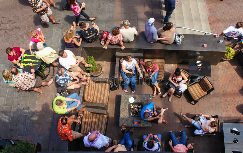 Bästa sikt av folk som omkring sitter med sommarkläder och leis, och drinkar i ett utvändigt sammanträdeområde och på tabeller på arkivbilder Bästa sikt av folk som omkring sitter med sommarkläder och leis, och drinkar i ett utvändigt sammanträdeområde och på tabeller på arkivbilder