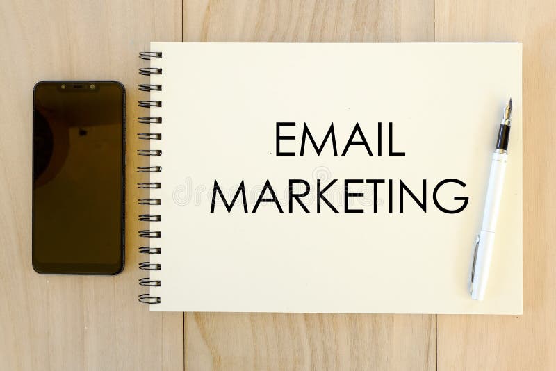 Bästa sikt av mobiltelefonen, pennan och anteckningsboken som är skriftliga med Emailmarknadsföring på träbakgrund royaltyfria foton Bästa sikt av mobiltelefonen, pennan och anteckningsboken som är skriftliga med Emailmarknadsföring på träbakgrund royaltyfria foton
