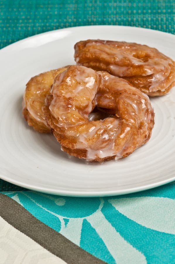 Bästa sikt av tre munkcrullers på en vit platta arkivfoto Bästa sikt av tre munkcrullers på en vit platta arkivfoto