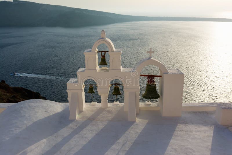 Båge med korset och klockor av den traditionella grekiska vita kyrkan i den Oia byn, Santorini ö, Grekland fotografering för bildbyråer Båge med korset och klockor av den traditionella grekiska vita kyrkan i den Oia byn, Santorini ö, Grekland fotografering för bildbyråer