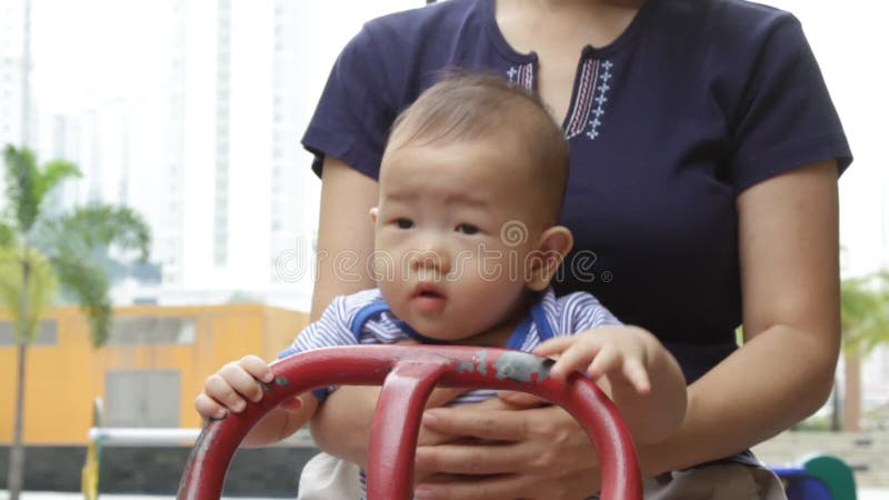 Bébé asiatique jouant sur la bascule