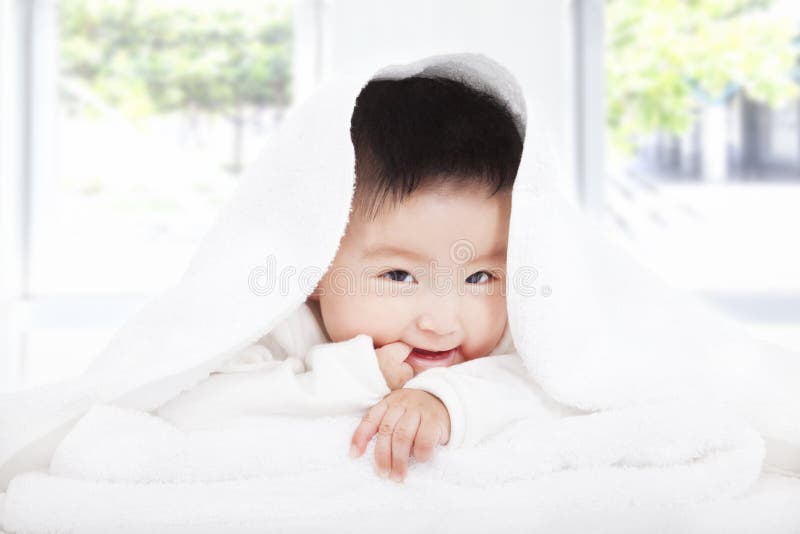 Bébé asiatique suçant le doigt sous la couverture ou la serviette images libres de droits Bébé asiatique suçant le doigt sous la couverture ou la serviette images libres de droits