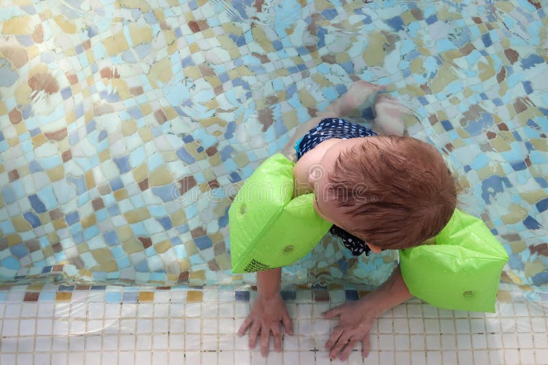 Bébé avec les brassards gonflables Enfant apprenant à nager dans la piscine image libre de droits Bébé avec les brassards gonflables Enfant apprenant à nager dans la piscine image libre de droits