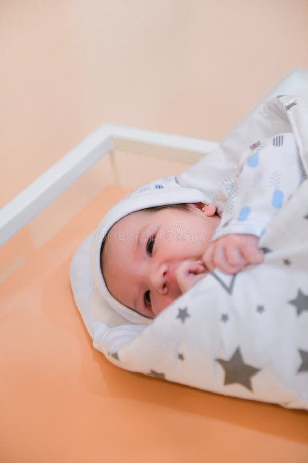 Bébé dans l'hôpital, se trouvant sur le sofa, enveloppé dans une couverture, décharge de l'enfant de l'hôpital de maternité, nais photos stock Bébé dans l'hôpital, se trouvant sur le sofa, enveloppé dans une couverture, décharge de l'enfant de l'hôpital de maternité, nais photos stock