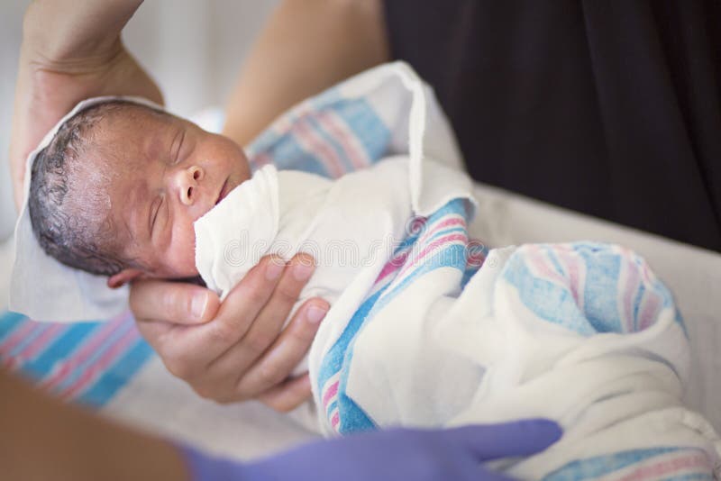 Newborn infant baby getting his first bath in the hospital. Cute little boy is bundled up and receiving a sponge bath by a nurse in his hospital room. Newborn infant baby getting his first bath in the hospital. Cute little boy is bundled up and receiving a sponge bath by a nurse in his hospital room