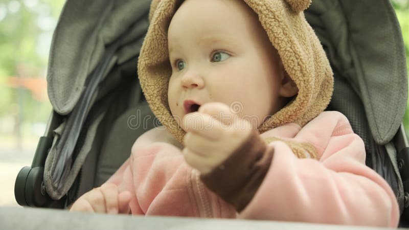 Bébé dégustant une collation en poussette dans le parc extérieur par une journée ensoleillée remplie de rire et de joie banque de vidéos