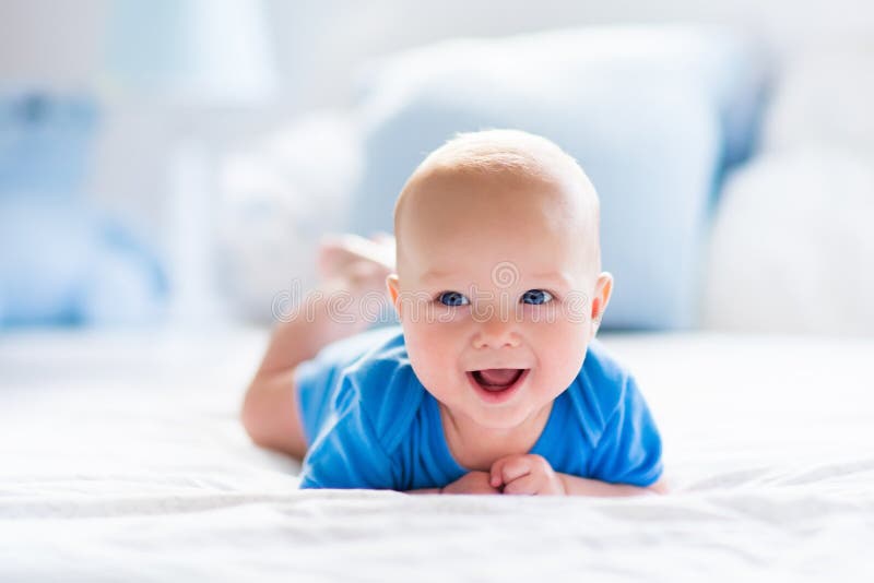 Bébé garçon dans la chambre à coucher ensoleillée blanche photo stock Bébé garçon dans la chambre à coucher ensoleillée blanche photo stock