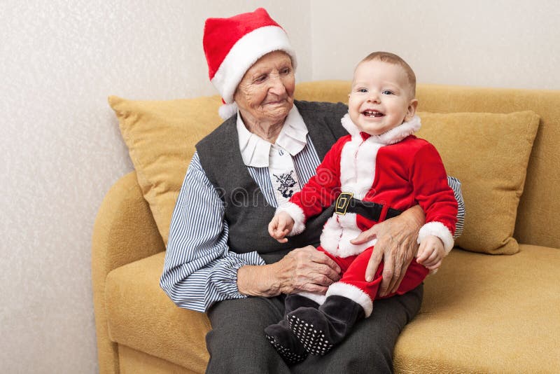 Bébé garçon dans le costume de Santa avec sa grand-mère photo libre de droits Bébé garçon dans le costume de Santa avec sa grand-mère photo libre de droits