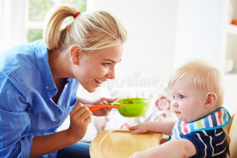 Bébé garçon de alimentation de mère dans la chaise d'arbitre images stock Bébé garçon de alimentation de mère dans la chaise d'arbitre images stock