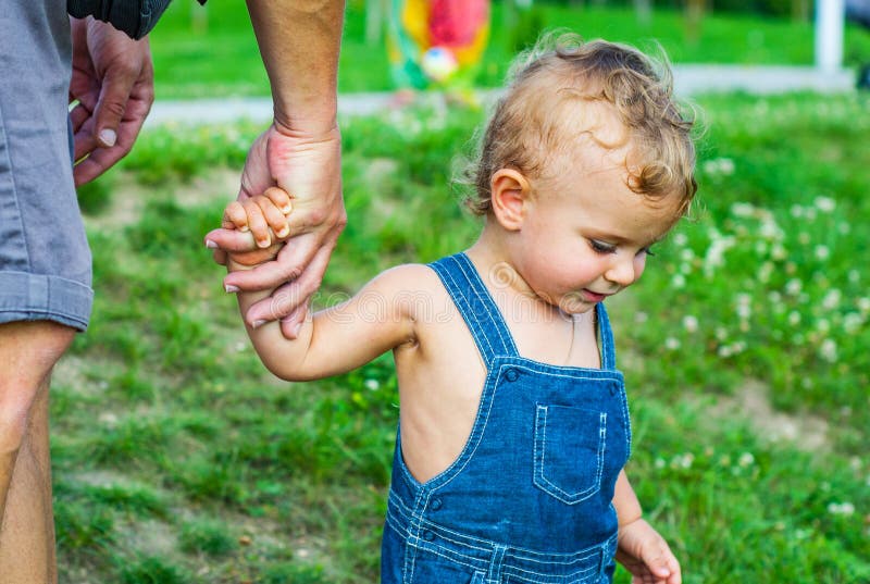 Bébé garçon en parc Faites confiance aux mains de famille du fils et du père d'enfant photographie stock Bébé garçon en parc Faites confiance aux mains de famille du fils et du père d'enfant photographie stock