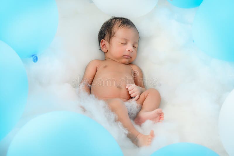 Bébé garçon infantile asiatique dormant sur le lit parmi le ballon bleu et blanc image stock Bébé garçon infantile asiatique dormant sur le lit parmi le ballon bleu et blanc image stock