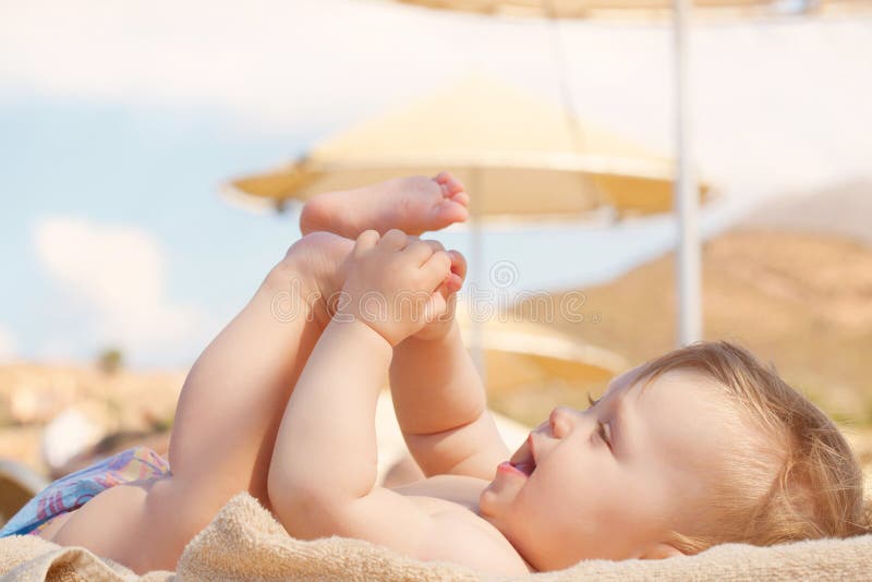 Bébé heureux sur la plage se trouvant sur le canapé photos stock Bébé heureux sur la plage se trouvant sur le canapé photos stock