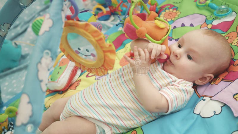 Bébé infantile jouant sur le tapis coloré Fermez-vous du jeu mignon de bébé garçon avec le jouet banque de vidéos