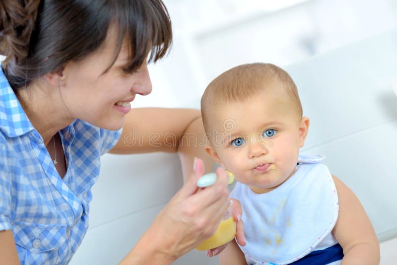 Bébé mangeant de la nourriture sur la cuisine photographie stock libre de droits Bébé mangeant de la nourriture sur la cuisine photographie stock libre de droits