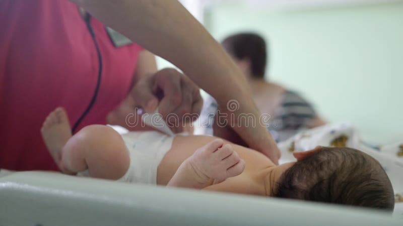 Newborn baby in maternity hospital - nurse is swaddling the infant, close up. Newborn baby in maternity hospital - nurse is swaddling the infant, close up